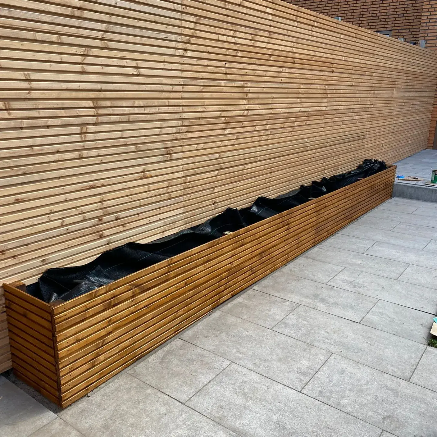 Long backyard planter box and privacy wall built with triple slatted Douglas Fir cladding board.