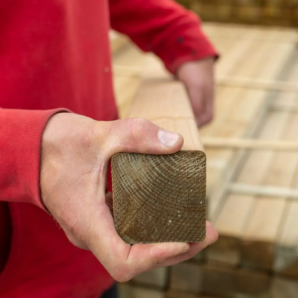 Close up hand-held cross-section view of a MicroShades square structural timber post showing growth rings and slightly rounded ease edges.