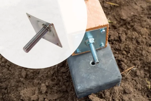 Installation reference view showing a screwable metal base plate attached to a timber post, ready to align with the center hole of an installed black concrete post base in the ground.