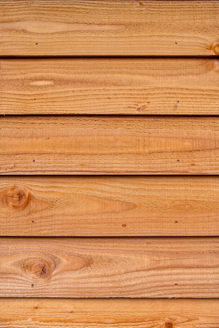 Close up texture view of installed Ecowood cladding boards in a traditional horizontal feather edge profile showing natural knots and wood grain.