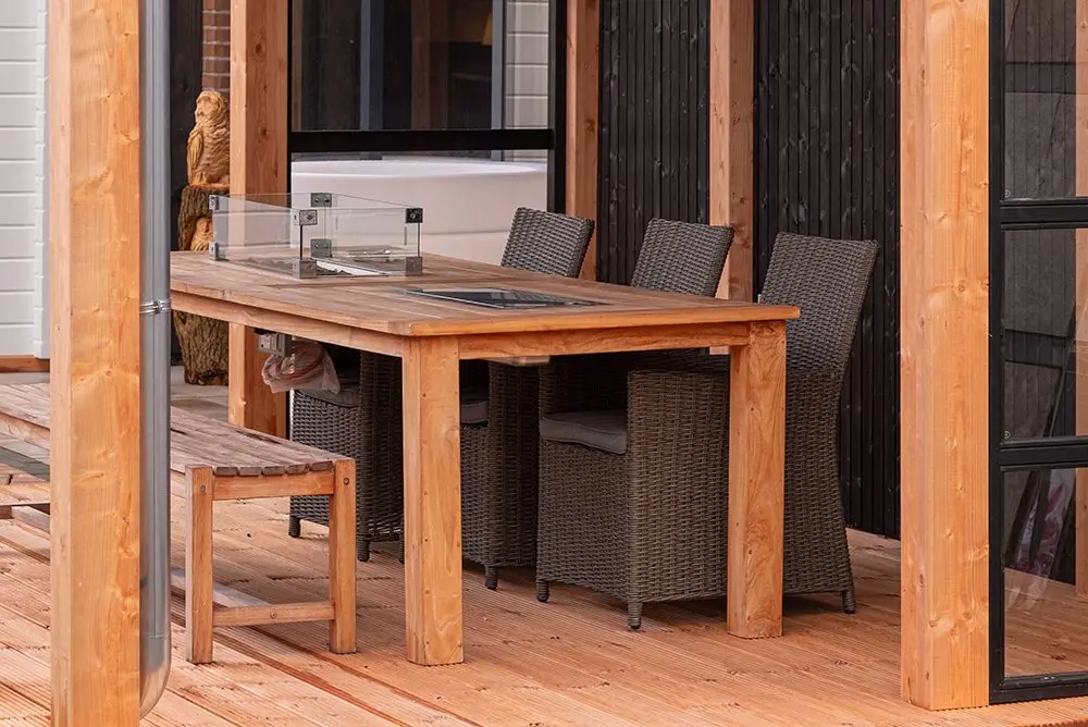 Outdoor dining patio setup with a wooden dining table and chairs on a deck built with Ecowood Decking Board Smooth Smooth 5000mm.