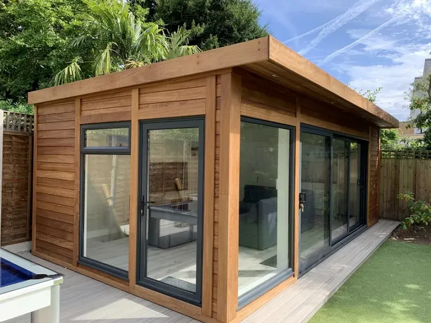 Installed horizontal Iroko hardwood cladding boards with a tongue and groove (T&G) profile on the exterior walls of a modern garden room office building with large glass windows.