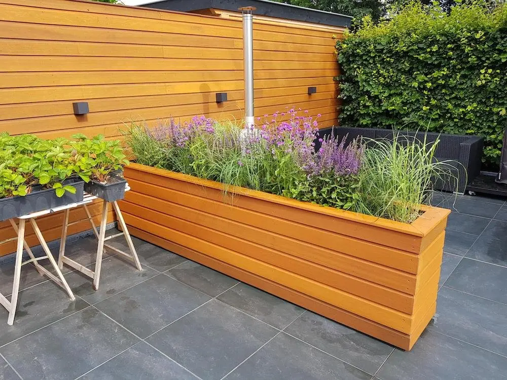 Iroko hardwood cladding boards used to construct a custom large garden planter box and matching privacy fence panel on a modern outdoor patio.