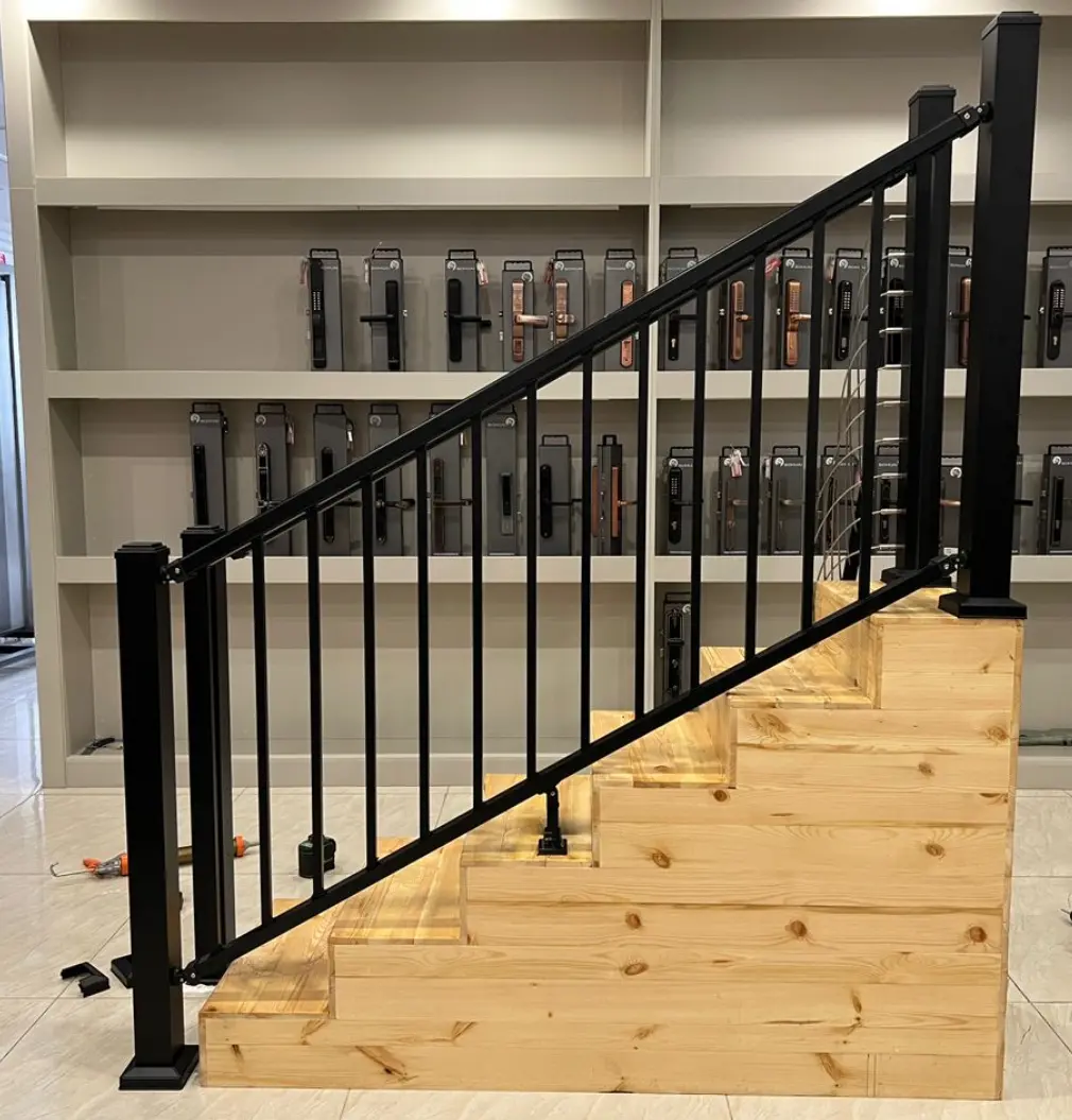 Black PuraFence aluminium stair balustrade railing kit featuring vertical spindles and matching posts installed on a wooden display staircase model.